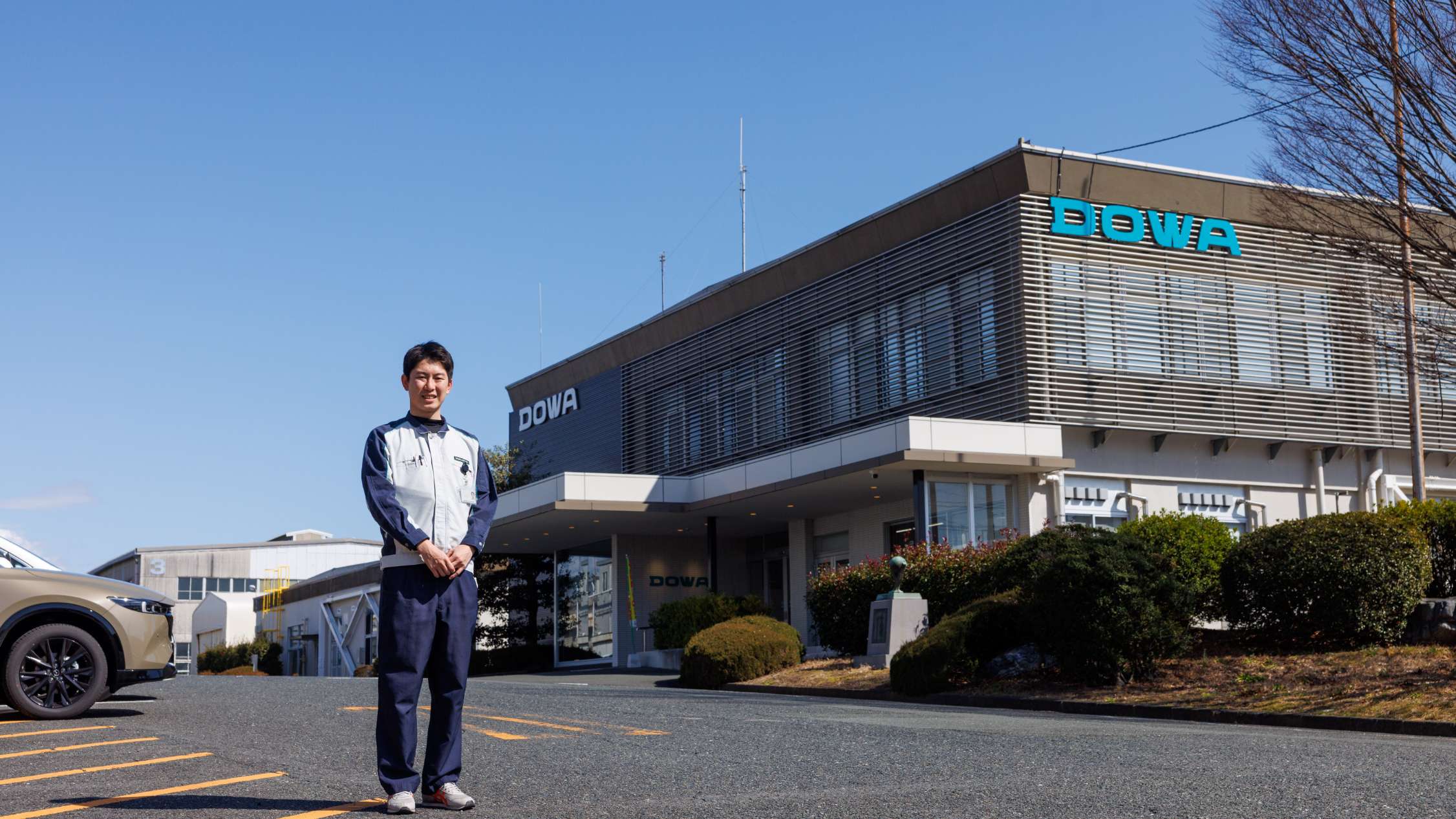 社屋を背に立つ笠谷さん